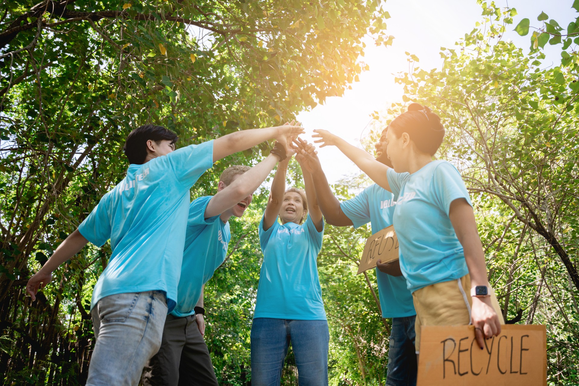 A Group of Volunteers stacks hands to help plant a forest to save the world in the forest park area., Environmental protection project.