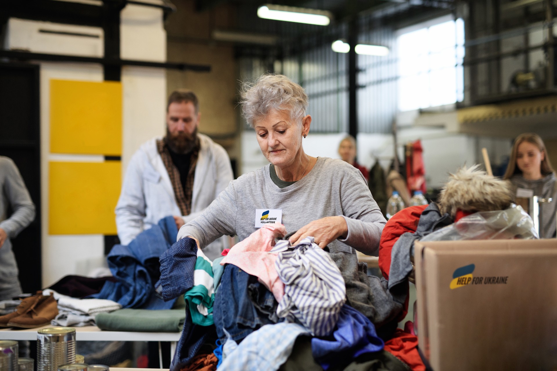 Volunteers sorting out donated clothes for the needs of Ukrainian migrants, humanitarian aid concept.