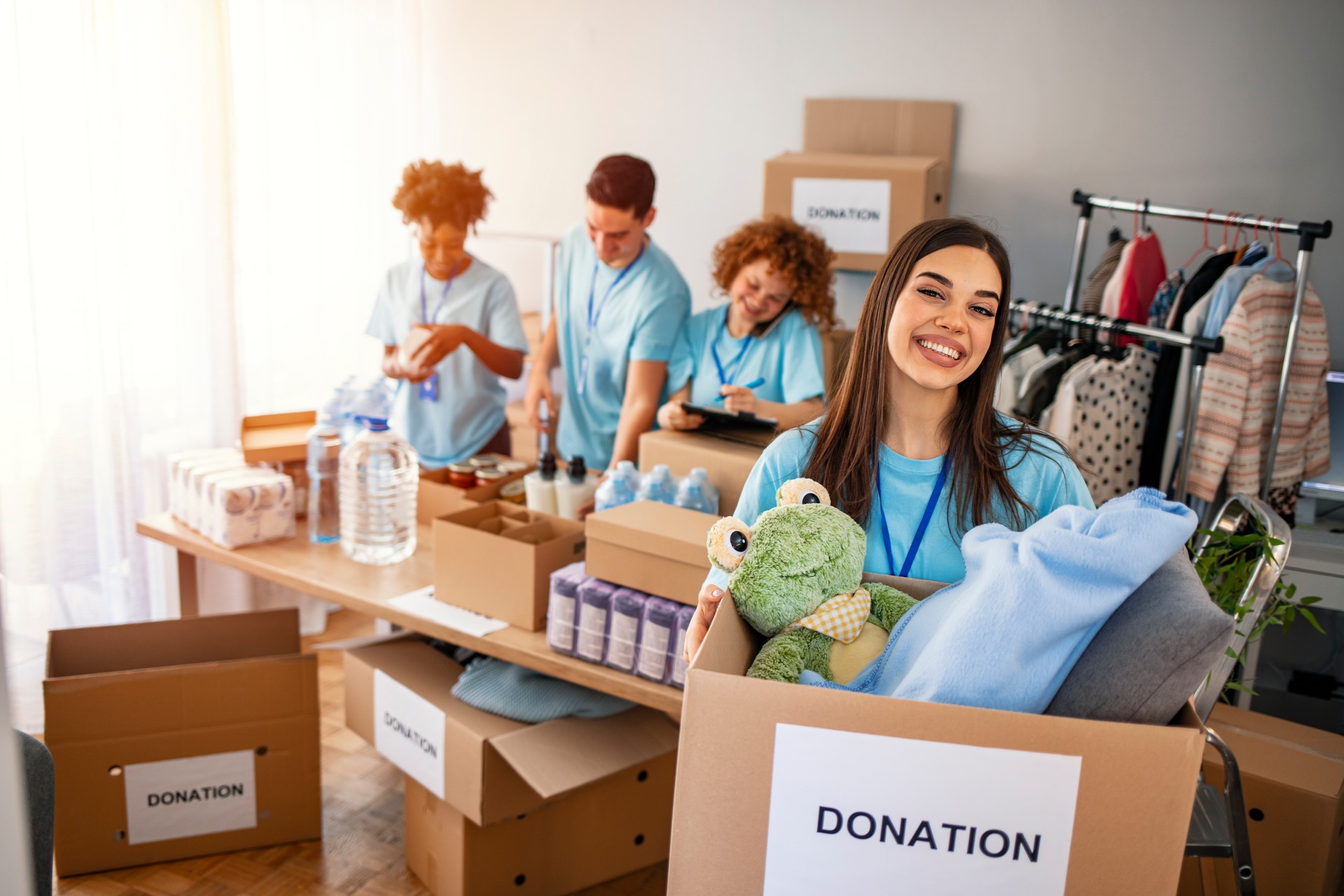 Woman volunteer holding a donation box and is smiling at the camera.