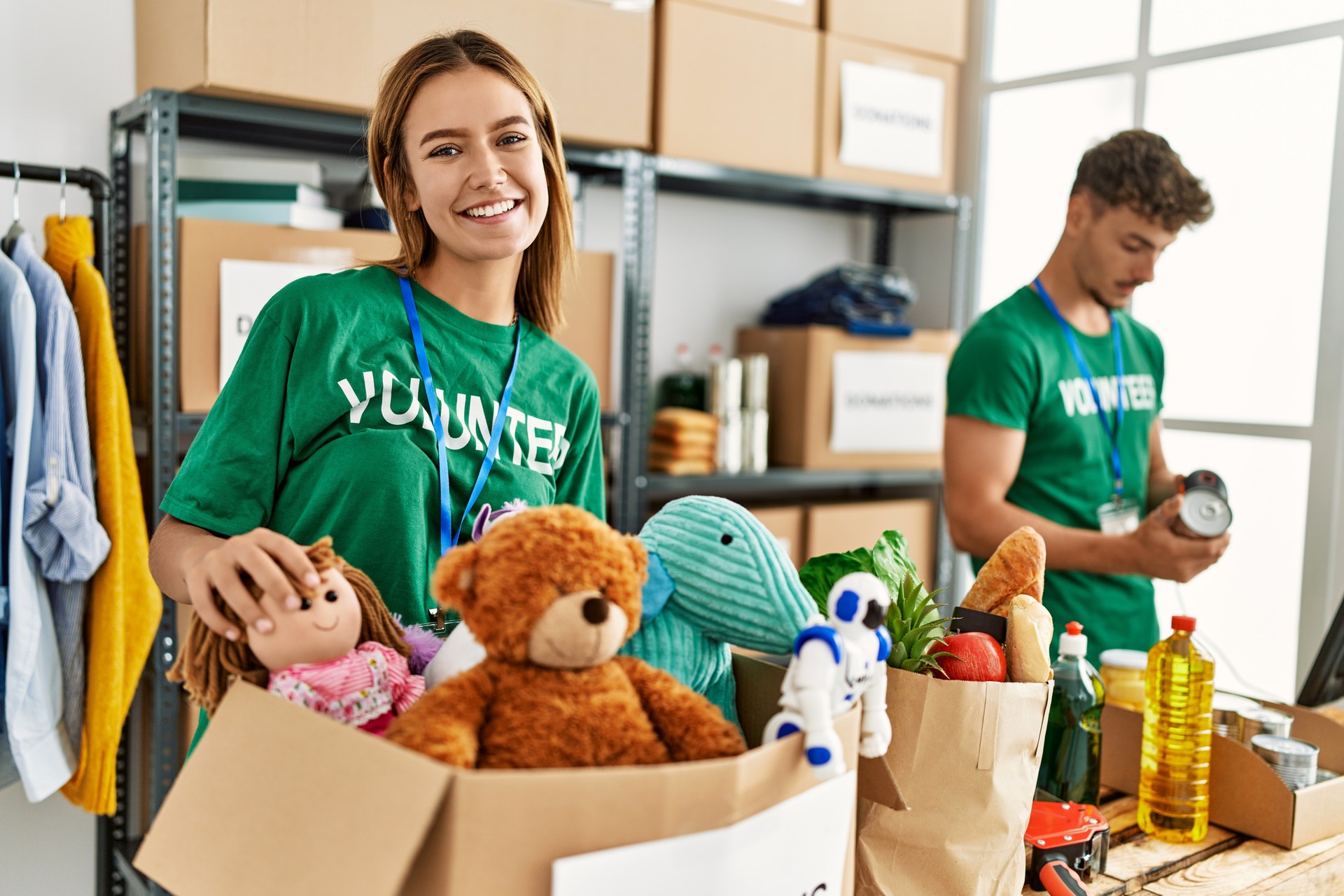 Young hispanic volunteer couple smiling happy working at charity center.